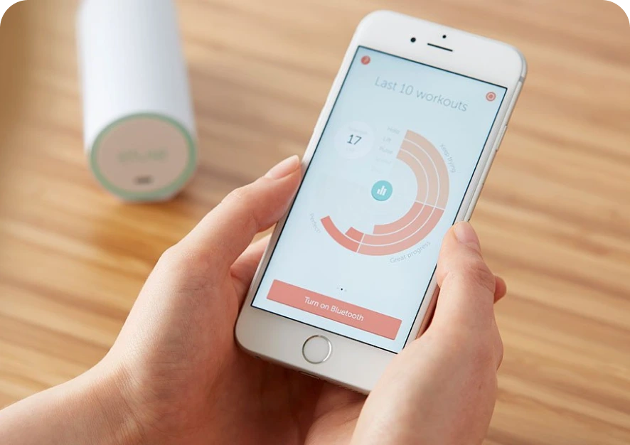 A human hand holding a smartphone showing a screenshot from Elvie Trainer app (