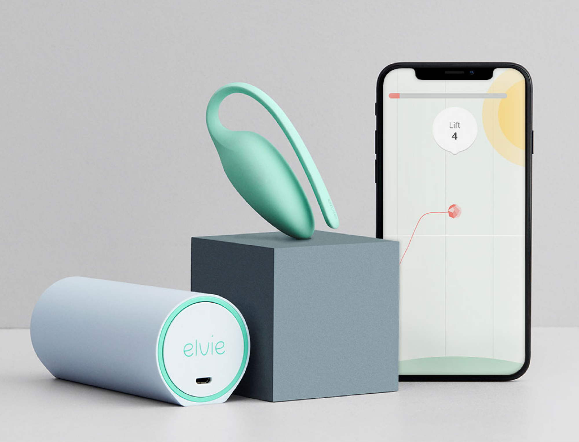 Pelvic health exerciser Elvie next to a smartphone with an Elvie app on.