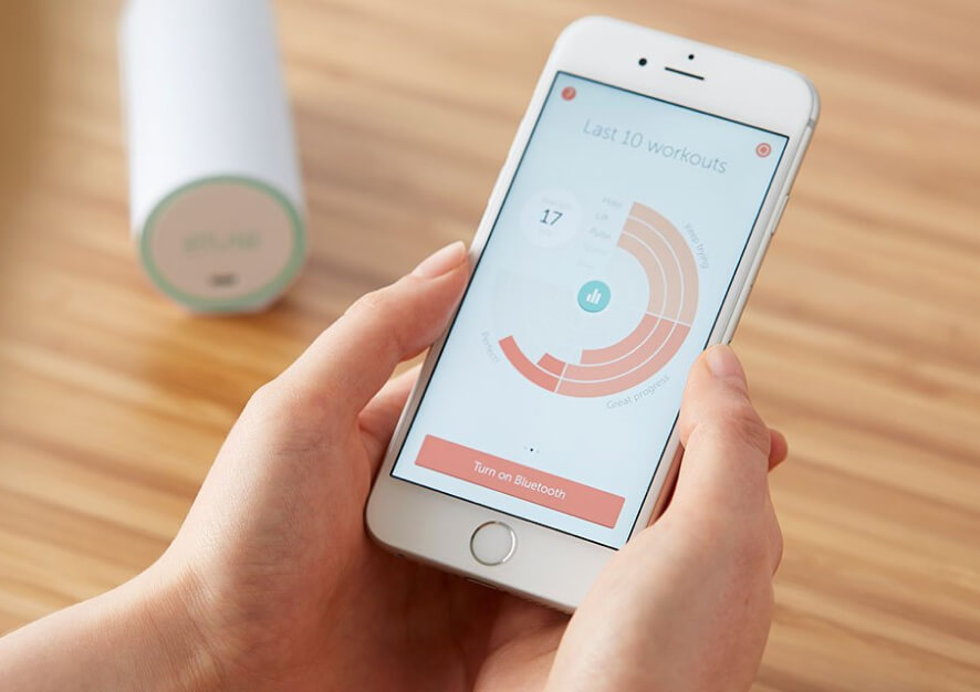A human hand holding a smartphone showing a screenshot from Elvie Trainer app (