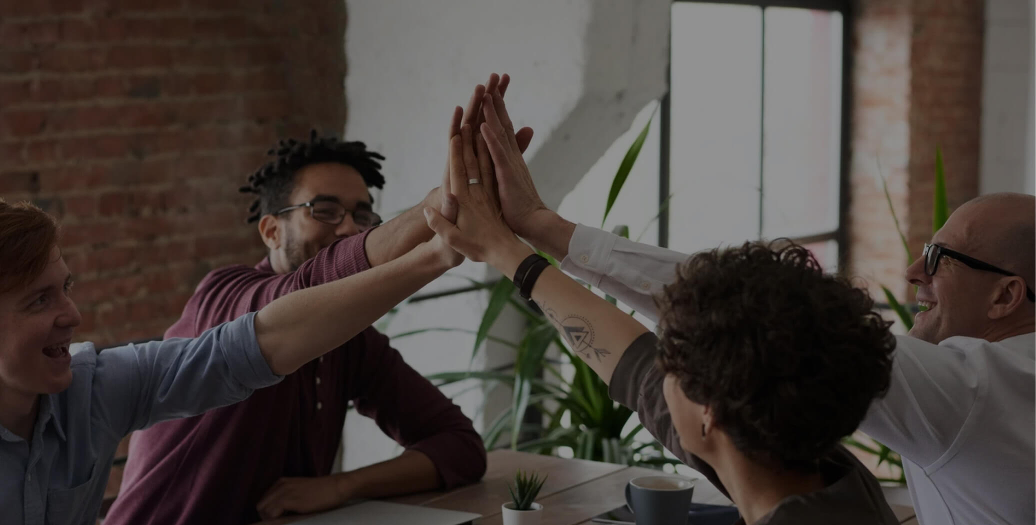 A group of people high-fiving each other while sitting at the desk.