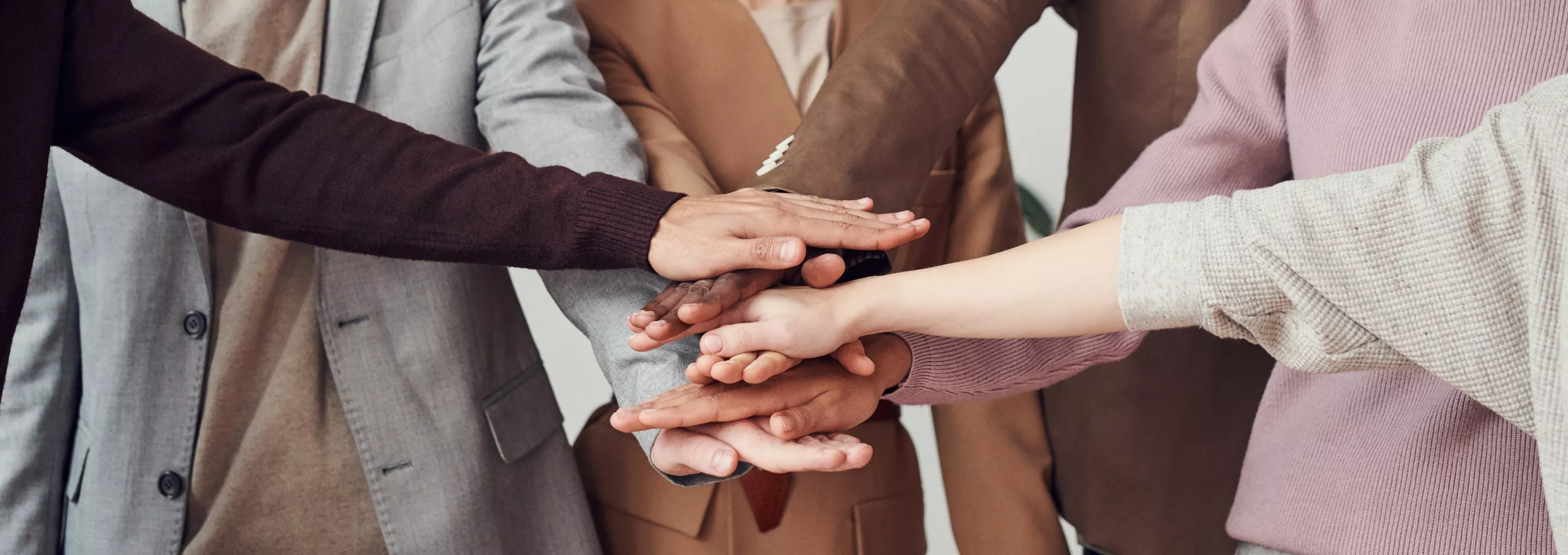 Close-up view of human hands of different races putting their hands together. Stack of hands showing unity.