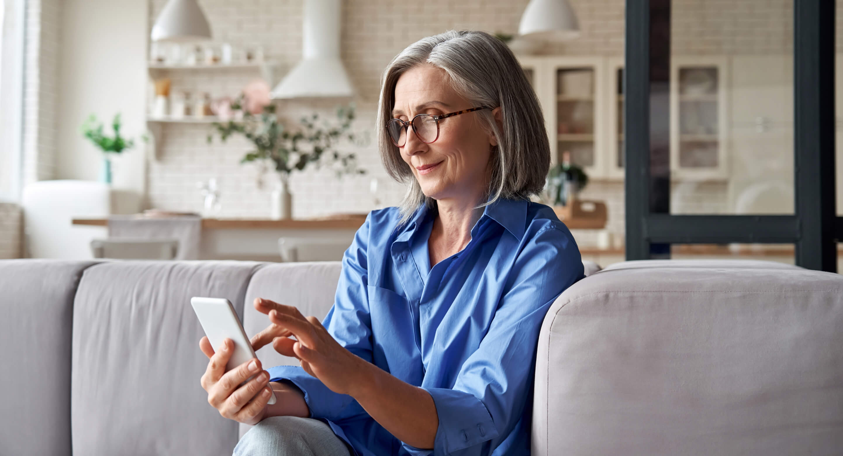 A white woman in her 50s, holding a smartphone and using a digital health app.