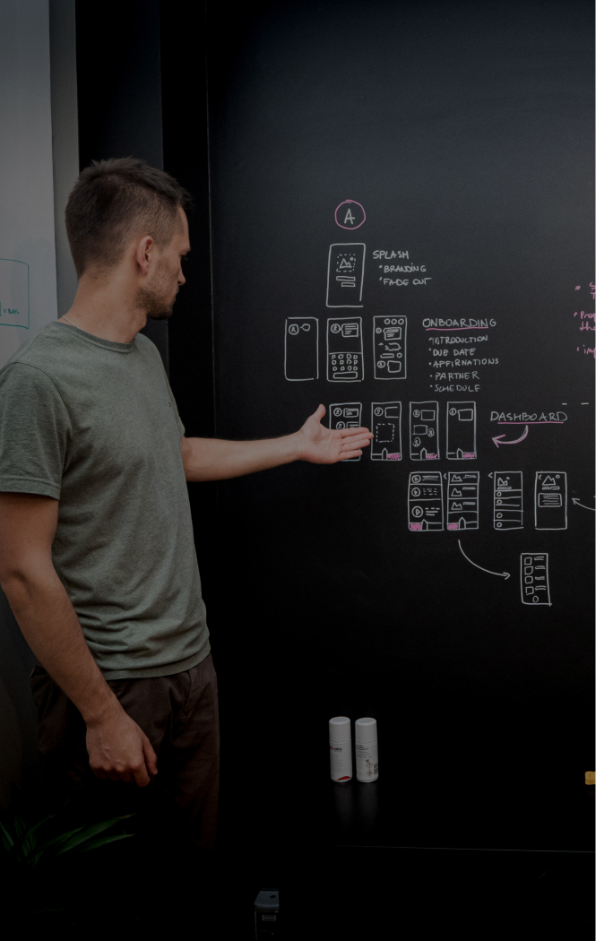 A silhouette of a man standing in front of a blackboard. He's pointing at the phone wireframes drawn on the board.